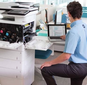 A man is checking the photocopier costs while injecting papers in it