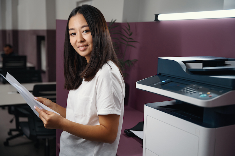 women standing next to a commercial copier costs