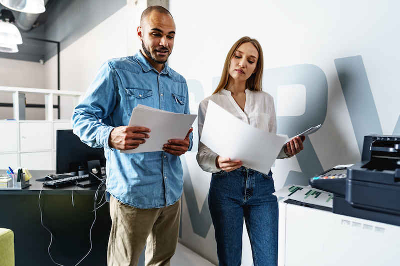 two coworkers talking about Key Factors to Consider When Choosing Copier Dimensions