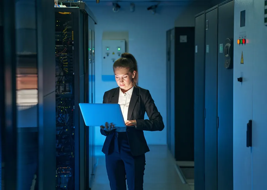 An engineer checking systems on a laptop in a server room