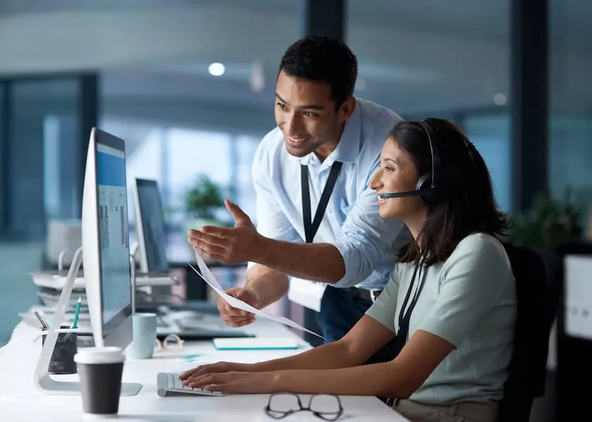An IT specialist helping a colleague at her desk