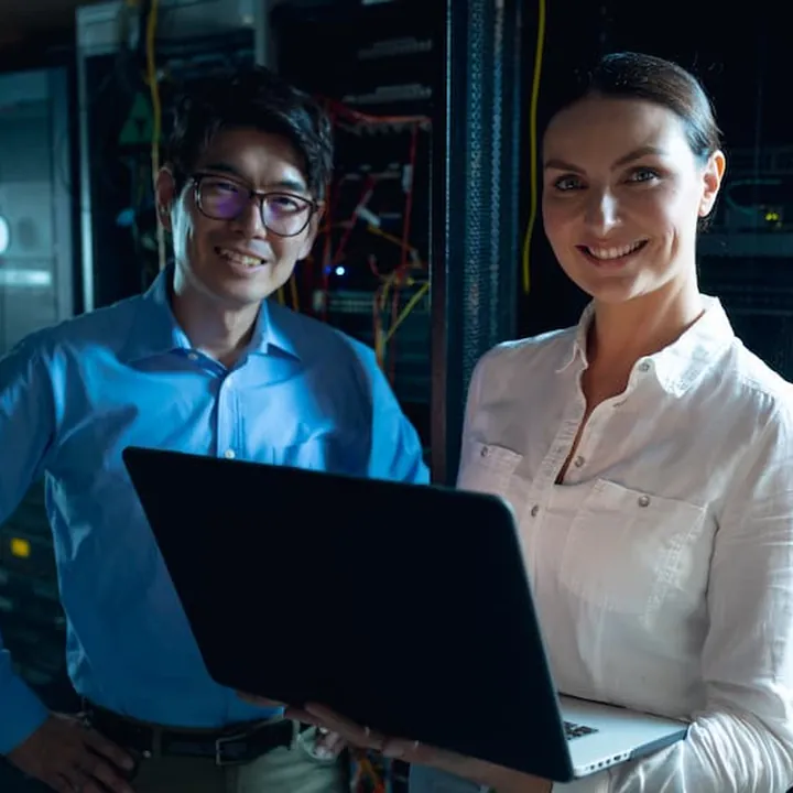 Two smiling IT engineers in a server room