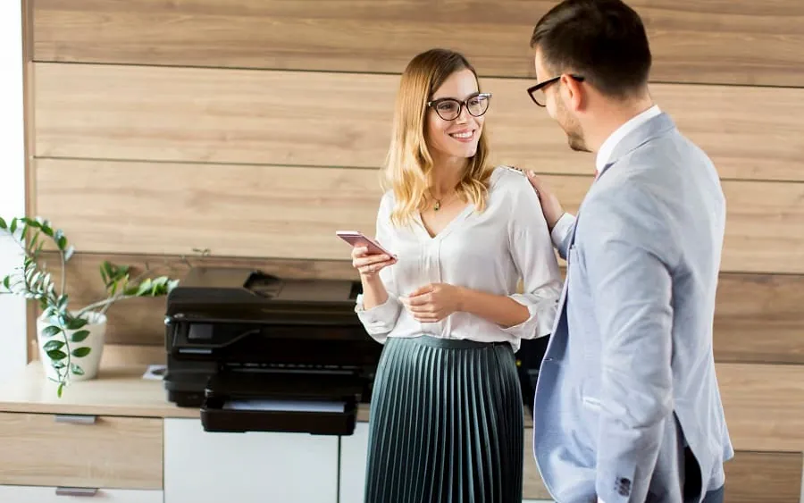 Two colleagues talking next to the office printer