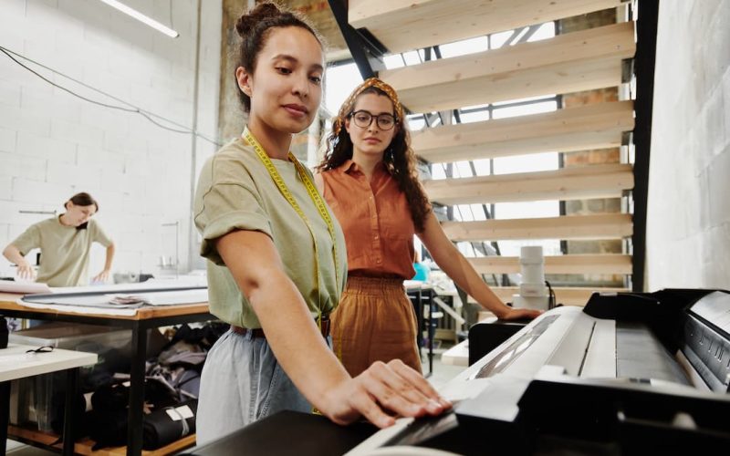 two-young-tailors-standing-by-large-format-printer Two women choosing copier machine